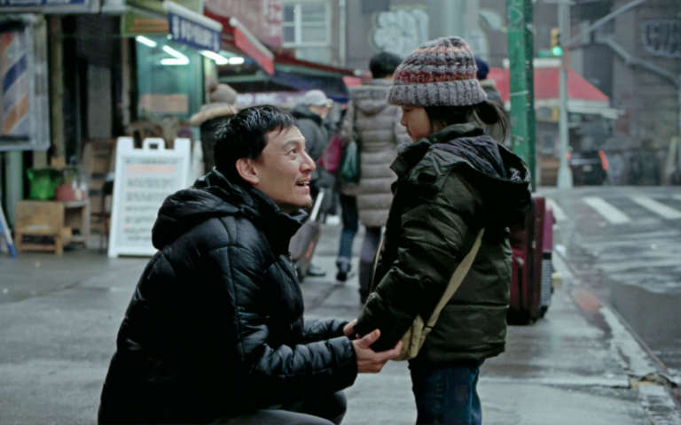 Chang Chen dans le rôle de Lu, agenouillé dans une rue de New York, tenant les mains de sa fille Yaya jouée par Carabelle Manna Wei, scène du film Les Lumières de New York