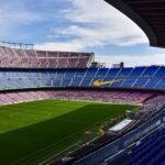 Wide view of the iconic Camp Nou stadium in Barcelona, showcasing its vast empty stands and lush green field.